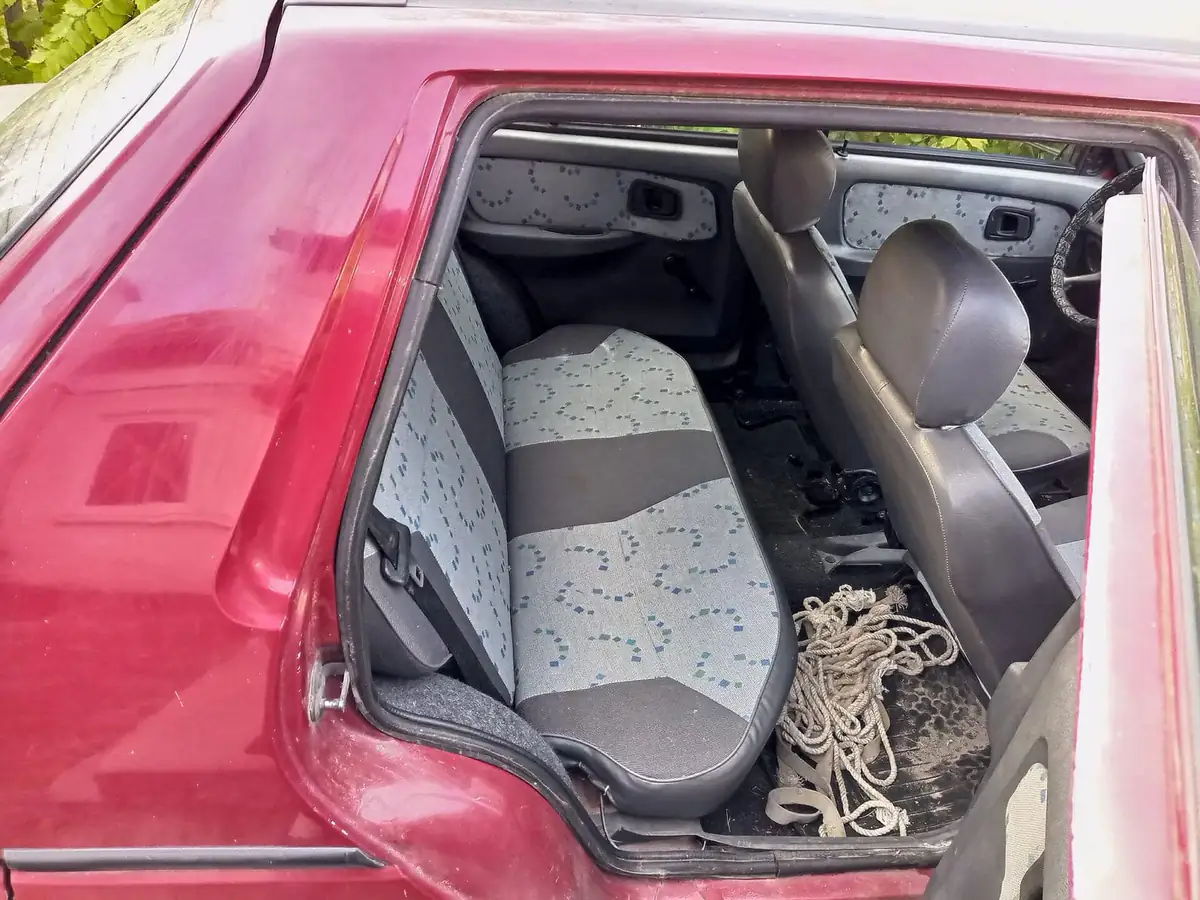 Rear car seats and cabin viewed through an open door, showing folds and rails