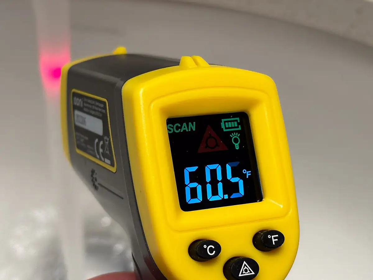 Yellow infrared thermometer gun displaying a temperature reading
