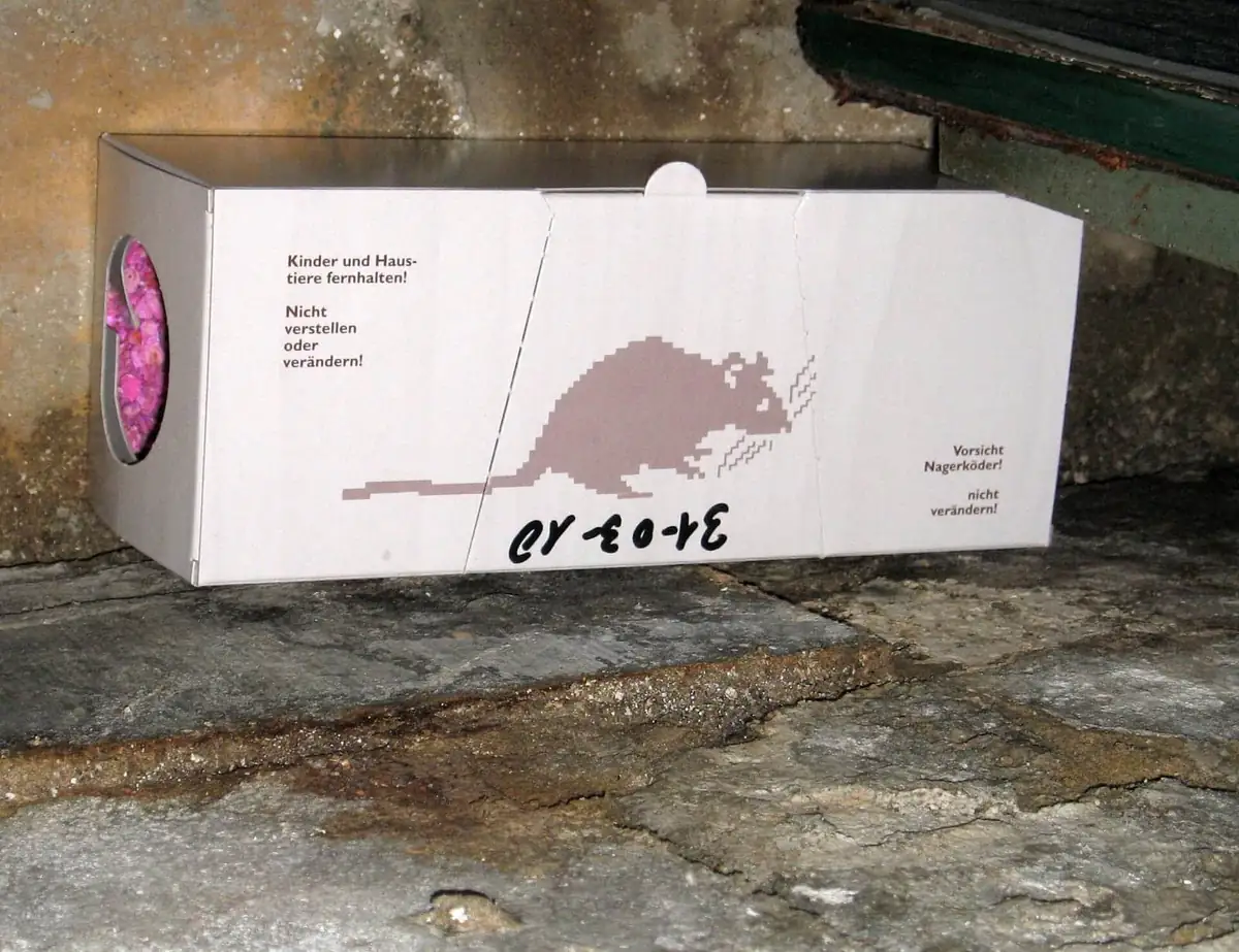Tamper-resistant rodent bait station placed against a wall