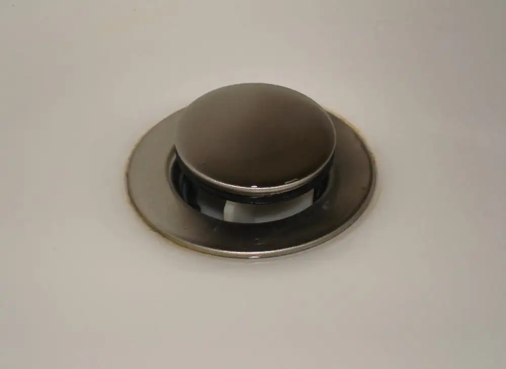 White bathroom sink with a chrome drain stopper, a classic breeding site