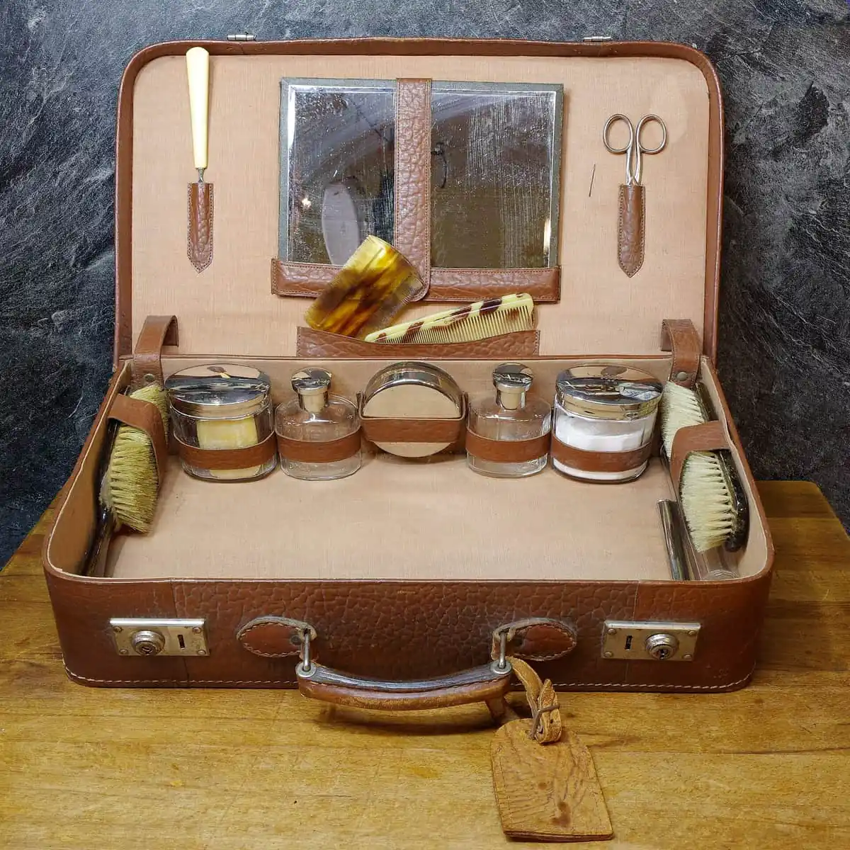 Open vintage suitcase packed with bottles, brushes, and grooming tools